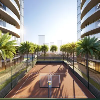 The image showcases a tennis court nestled among palm trees and sleek glass buildings. The sun creates striking shadows, highlighting the modern luxury living environment with high-rise towers against a clear blue sky. Experience this blend of sport and sophistication with Redlac Real Estate in Dubai, where premium lifestyle meets architectural elegance.