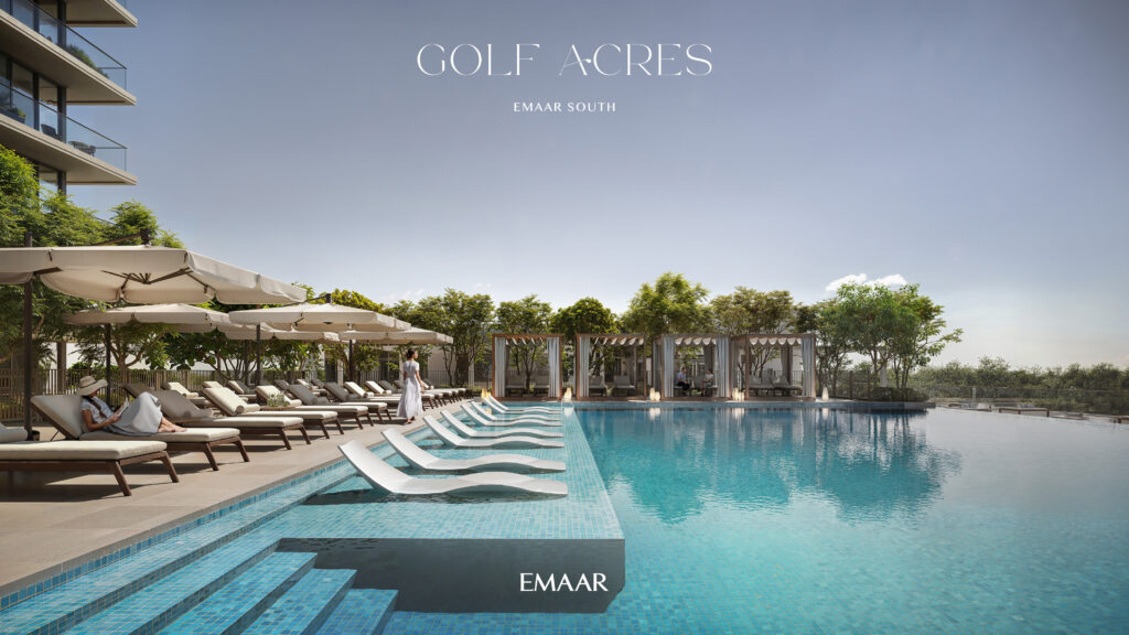 A tranquil outdoor pool, surrounded by lounge chairs and umbrellas, features a person in a white robe by the water. Modern cabanas with lush greenery complete the elegant scene. Discover such luxurious living with Redlac Real Estate in Dubai—your gateway to prestigious properties at Emaar Souths Golf Acres and beyond. Experience unparalleled elegance today!.