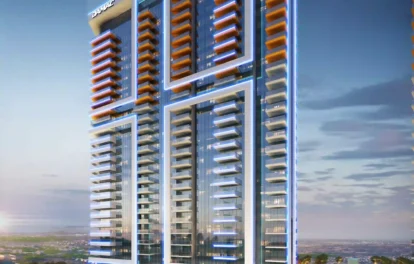 The image showcases Golf Gate 2, a sleek high-rise in Dubai with blue and orange lights set against a dusky sky. It features two towers offering luxurious apartments with breathtaking golf course views. Numerous balconies and a curved entryway enhance its appeal, surrounded by lush trees and pathways. Discover this gem through Redlac Real Estate, your key to elegant living in Dubai’s prime locations!.