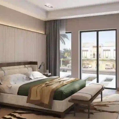 Explore modern living with Redlac Real Estate in Dubai. This Sun City bedroom features a spacious bed adorned with green and beige bedding, accompanied by a stylish bench at the foot. Elegant bedside tables with lamps flank the bed, while a large window offers scenic views of palm trees and vibrant city streets. Enjoy your sanctuary in neutral tones and soft lighting that exudes cozy sophistication.