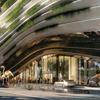 The Twin-Tower Residences, a stunning example of modern architecture, showcases curved, layered designs adorned with lush greenery. A reflective surface highlights a grand flamingo sculpture outside. Near the entrance, expansive glass windows overlook parked cars. Discover such unique properties with RedLac Real Estate in Dubai, where innovative design meets luxury living.