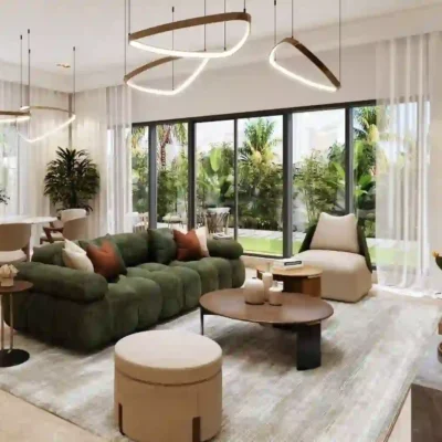 Discover modern elegance with a living room in Sun City, showcasing a green sofa, round coffee table, and tan ottoman on a spacious gray rug. Unique hanging lights enhance the ambiance, while large windows offer serene garden views complemented by lush plants. A dining table adds sophistication in the background. Explore exquisite homes like this with Redlac Real Estate in Dubai for unparalleled luxury living.